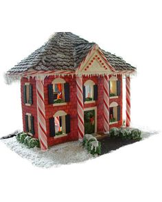 a red and white christmas house with candy canes on the front windows, and snow on the ground