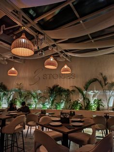 the interior of a restaurant with tables, chairs and hanging lights above it is decorated with palm trees