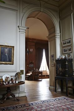 an archway leading into a living room filled with furniture and paintings on the walls,