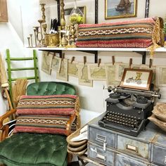 an old fashioned typewriter sitting on top of a desk next to a green chair