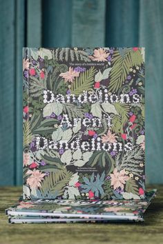 a book sitting on top of a wooden table next to a blue wall with flowers and leaves