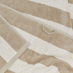 a white and brown striped towel laying on top of a bed next to a pillow