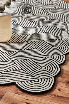 a black and white rug on the floor next to a table with two candles in it