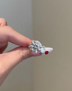 a woman's hand holding a diamond ring with red and white designs on it