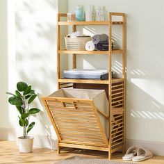 a wooden shelf with towels and other items on it next to a potted plant