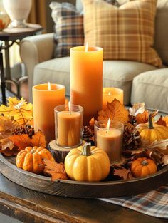 a tray filled with candles and pumpkins on top of a table next to a couch