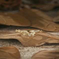 a gold ring sitting on top of a leaf covered ground with leaves around the band