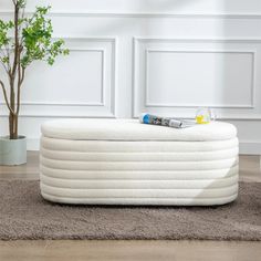 a white mattress sitting on top of a brown rug next to a potted plant