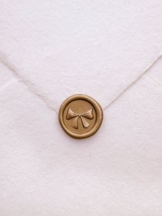 a close up of a button on a white envelope with a gold colored metal bow