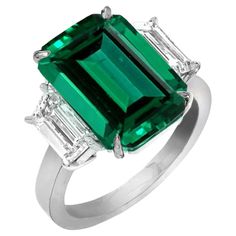 An exquisite 4 carat green emeald with practically no inclusions and a vivid green color! The side EXQUISITE EMERALD AND DIAMOND RING This marvelous 3 stone styled ring sports a Rare Emerald weighing 4 cts. The real eye catcher of this beautiful Emerald ring is surrounded by glimmering trapezoid diamonds that really bring out the deep forest green hue of this rare yet classy Emerald. Trapezoid Diamonds weight approximately 1 carats are E-F color and VVS clarity The ring has been handmade in Ital Green Engagement Rings, Chrome Green, Jewelry Knowledge, Deep Forest Green, Emerald Wedding Rings, Emerald Cut Diamond Ring, Emerald And Diamond Ring, Three Stone Diamond Ring, Platinum Diamond Engagement Rings