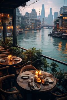 an outdoor dining area overlooking the water with candles lit on tables and chairs in front of it