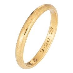 an 18ct gold wedding ring with the word'love'engraved on it, in front of a white background