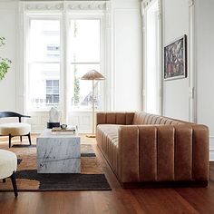 a living room filled with furniture and a marble coffee table on top of a hard wood floor