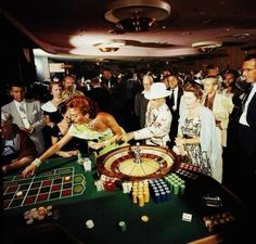 a group of people standing around a rouleette in a room full of other people