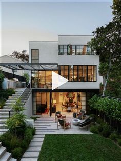 a modern house with stairs leading up to the upper floor and an outdoor dining area