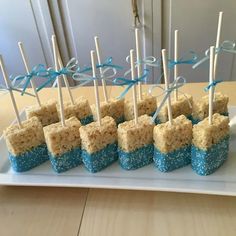 rice krispy treats with toothpicks are arranged on a white plate and tied in blue ribbon