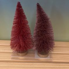 two small red trees sitting on top of a wooden table