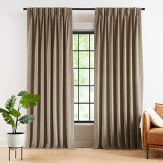 a living room with a couch, chair and window covered in beige drapes