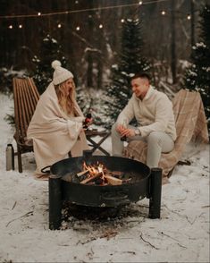 two people sitting around a campfire in the snow