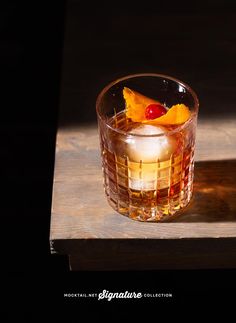 a glass filled with an alcoholic drink sitting on top of a wooden table