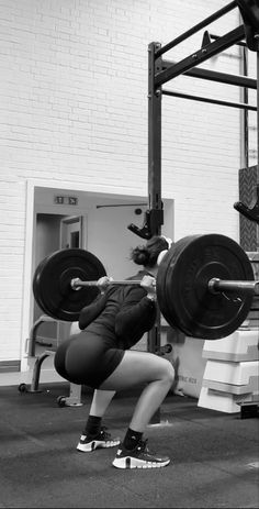 a woman is squatting while holding a barbell