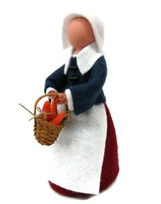 a doll holding a basket with carrots in it's hand on a white background