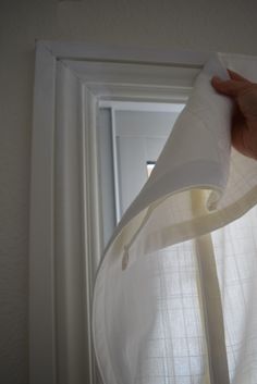 a person holding a piece of white paper in front of a window with the curtain pulled back