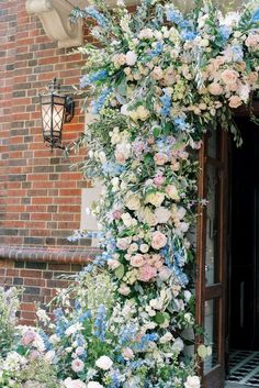 an archway covered in flowers next to a brick building