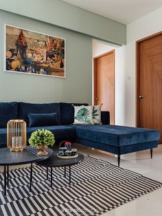 a living room with a blue couch and coffee table in front of a painting on the wall