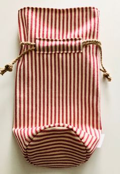 a red and white striped bag with rope on it's side, sitting on a table