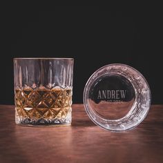 an empty whiskey glass next to a shot glass with the name and logo on it