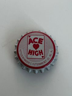 a red and white bottle cap with ace high logo on it sitting on a table