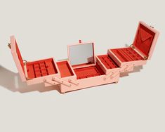 an open pink box with red compartments and gold handles