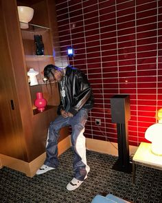 a man sitting on a stool in a room with red tile walls and flooring