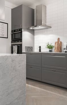 a kitchen with gray cabinets and marble counter tops