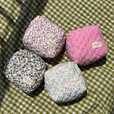 four cloth baby diapers sitting on top of a green and white checkered blanket