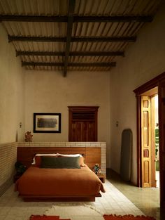 a bed sitting in a bedroom on top of a tiled floor next to a doorway