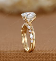 a gold ring with a pear shaped diamond on top and side stones around the band