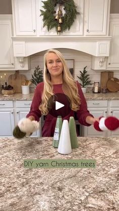 a woman standing in front of a kitchen counter with christmas decorations on top of it