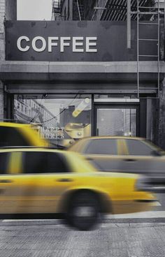 two taxi cabs driving past a coffee shop