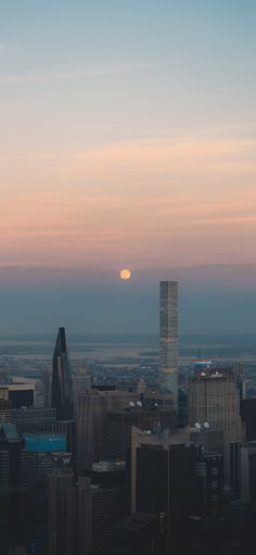 the sun is setting over a city with tall buildings and skyscrapers in the foreground