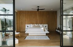 a bedroom with wood paneling and white bed in the center, as seen through glass doors