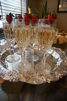 several glasses of champagne on a tray with strawberries