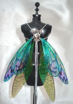 a mannequin wearing a green and blue fairy wings costume with jewels on it