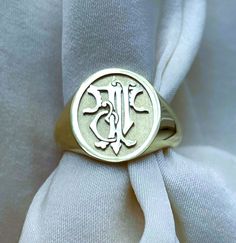 a signet ring with the letter j is shown on top of a white cloth