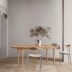 two chairs and a table in an empty room with plants on the table, one chair is black