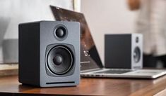 a laptop computer sitting on top of a wooden desk next to speakers and a speaker system