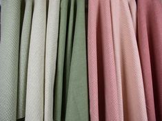 many different colored fabrics hanging on a rack