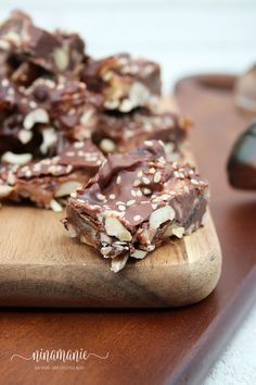 a wooden cutting board topped with pieces of chocolate and nutty bars on top of it