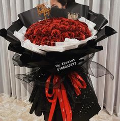 a large bouquet of red roses is wrapped in black paper